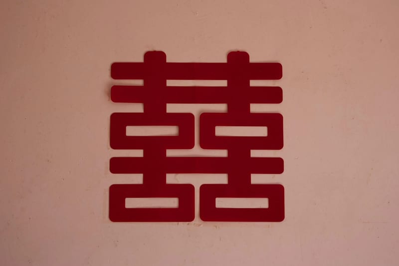 红色囍字剪纸贴在粉色墙面上，画面中没有人。